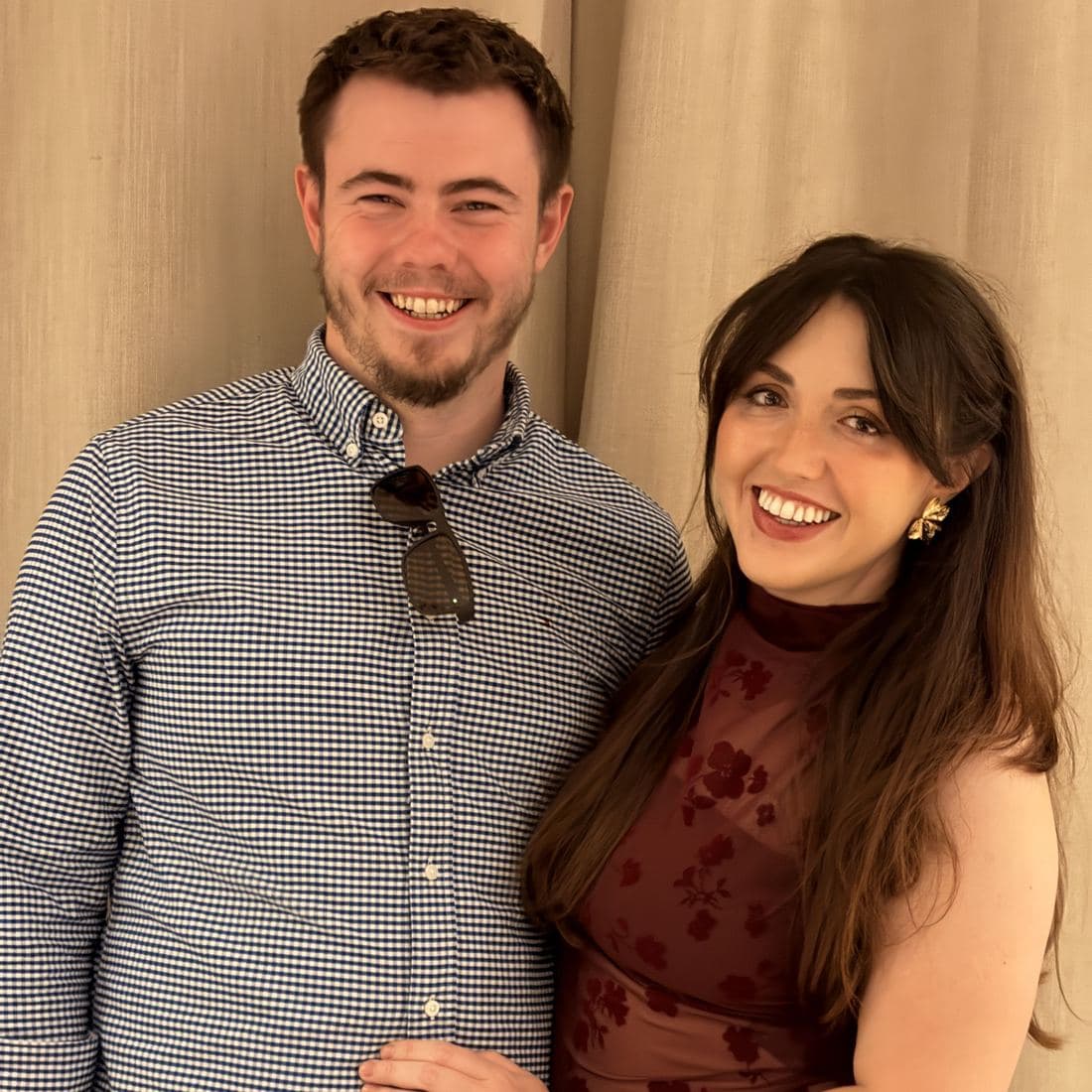 Conor and Erin standing arm in arm, dressed up and grinning at the camera